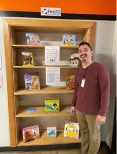 Person standing in front of a bookshelf with exemplar children's books.