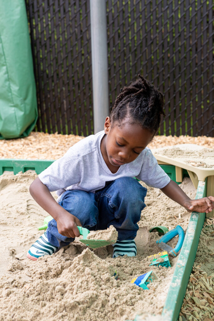 Little Black girl playing in a sandbox.